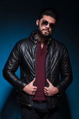 young man with long beard is holding his leather jacket