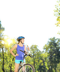 Naklejka premium Young female biker posing on a mountain bike on sunny day