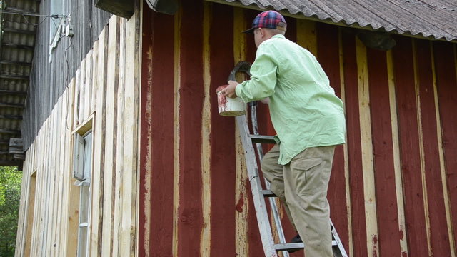 worker climb ladder to the wall paint wooden wall with red paint