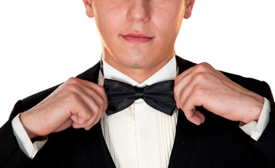 man in a black suit adjusts his bow tie close-up face