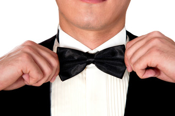 man in a black suit adjusts his bow tie close-up face