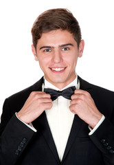 cheerful man in a black suit adjusts his bow tie