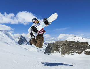 Snowboarder jumping on background of mountains