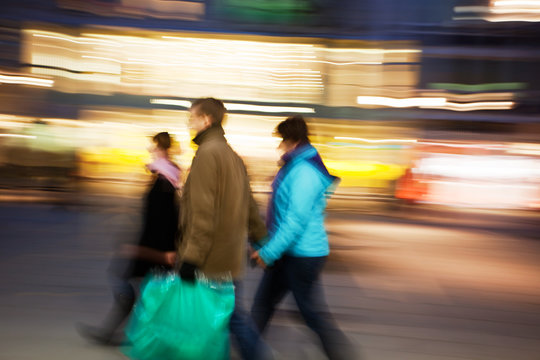 Couple with shopping bags walking past at dusk