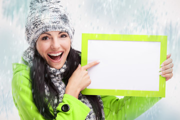 smiling girl pointing at a blank board and around snowing