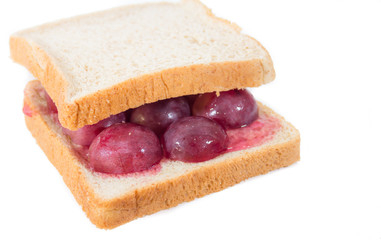 A grape jelly sandwich on wheat bread that has been bitten on a