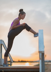 Healthy young woman stretching outdoors in the evening