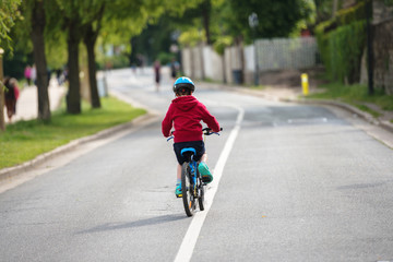 young child doing the bike alone in the middle of the road