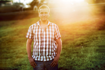 Young casual man standing on the green grass in the park