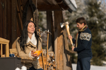 Couple by snow winter cottage enjoying tea