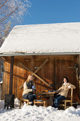 Two girlfriends enjoy tea snow winter cottage