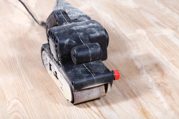 hand-held belt sander sanding wooden surface