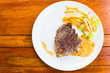 beef steak on white dish with salad and french fries