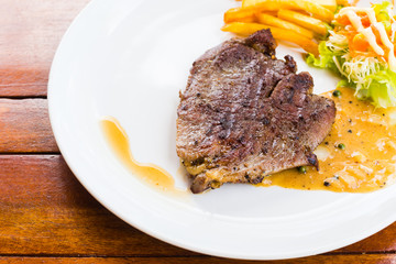 beef steak on white dish with salad and french fries