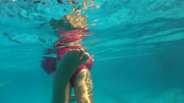 A little girl swimm in pool. the camera goes under water