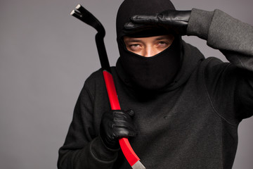 Burglar with a crowbar on the shoulder.