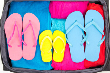 travel suitcase with clothing and flip-flops