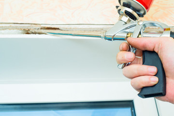 Nail gun being used to install trim around window