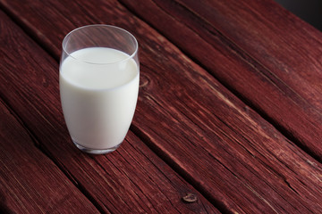 Glass of milk standing on old wooden table