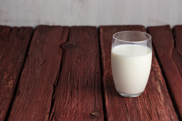 Glass of milk standing on old wooden table