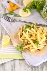 French fries on tracing paper on board on napkin wooden table