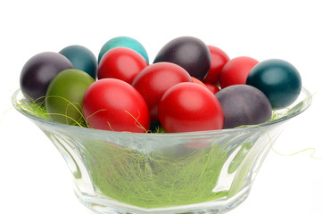 Close up on hand dyed easter eggs in a glass bowl with grass