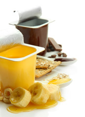 Tasty desserts in open plastic cups and banana, isolated