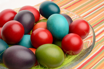 Easter eggs in a bowl on a table with striped tablecloth
