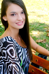 Girl smiling sitting on a bench in the park on a hot summer day