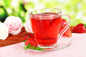Delicious strawberry tea on table on bright background