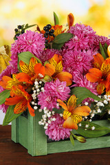 Flowers composition in crate on table on bright background