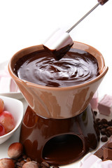 Chocolate fondue with marshmallow candies and fruits, isolated