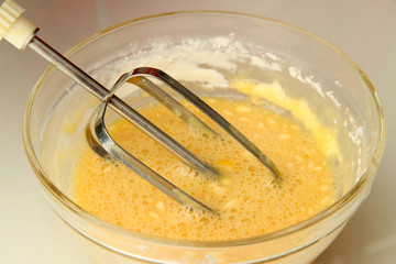 Cooking, whipping eggs with electric whisk in bowl, close up