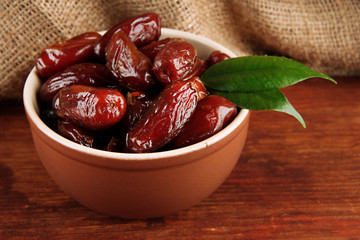 Dried dates in bowl on table on sackcloth background