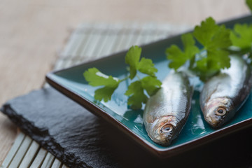 Fresh tasty raw sprats on serving dish
