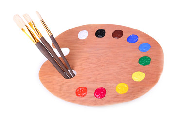 Wooden art palette with paint and brushes isolated on white