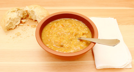 Soup on a table with a torn bread roll