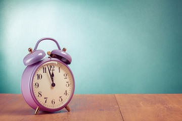 Retro violet alarm clock on desk front mint green background