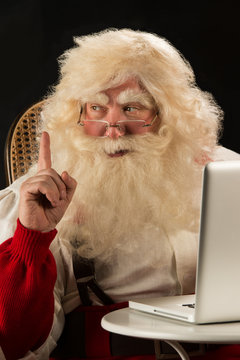 Santa Claus working on computer and having great idea