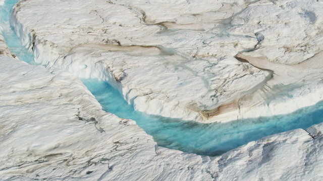Aerial view ice blue water cutting across frozen glacier, USA