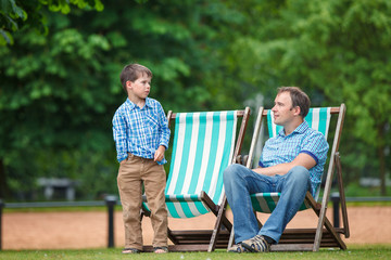 Happy father and son having rest in city park on summer day