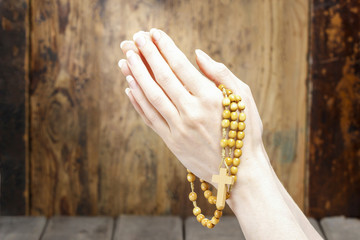 Hands holding wooden rosary