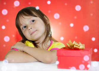 Little girl sitting next to gift box and thinking what's in it