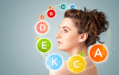 Pretty young girl with colorful vitamin icons and symbols