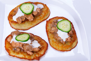 Potato pancakes with chicken and mushrooms sauce on the plate