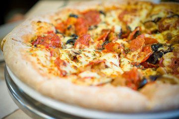 Fresh little italia pizza with pepperoni sausages and olives on