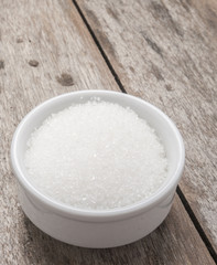 sugar in white bowlon wooden background