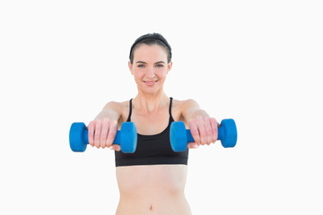 Fototapeta na wymiar Portrait of a smiling young woman with dumbbells