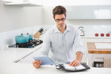 Naklejka na ściany i meble Casual man with digital tablet using a diary in kitchen