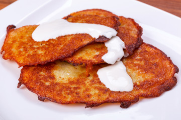 Potato pancakes with sour cream on the plate